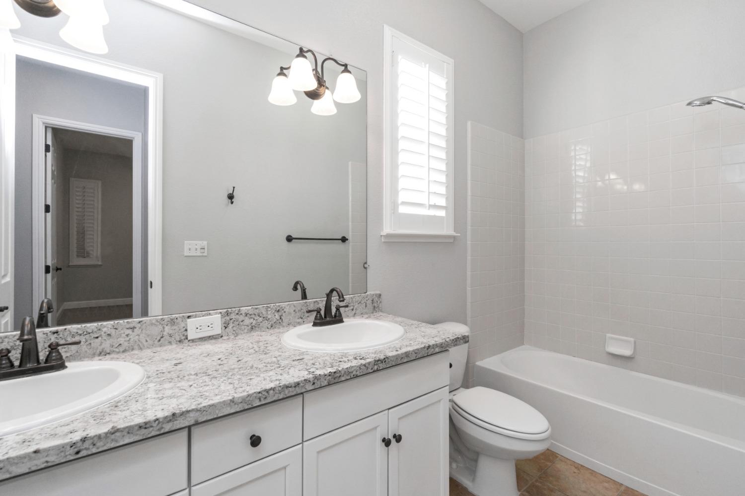 3307 Buckingham Avenue Clovis, CA 93619 - Photo 20 of 32 a bathroom with a granite countertop sink a toilet and bathtub
