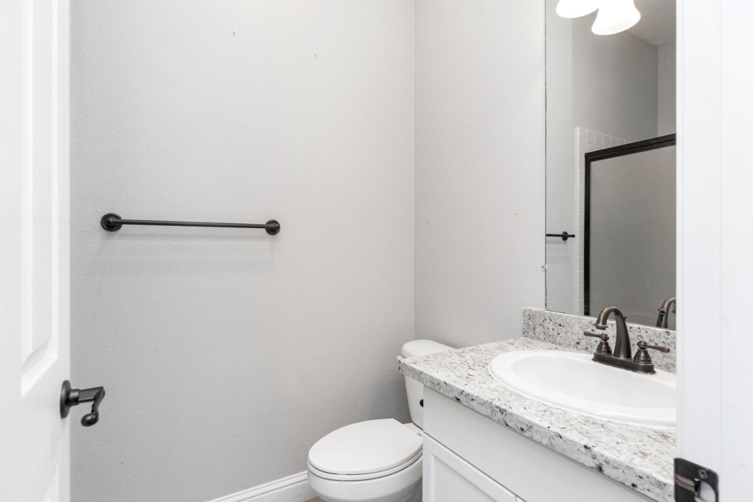 3307 Buckingham Avenue Clovis, CA 93619 - Photo 23 of 32 a bathroom with a granite countertop sink toilet and a mirror