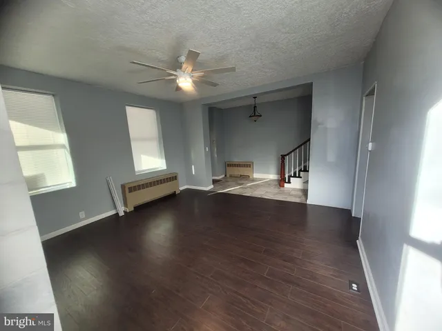 an empty room with wooden floor fan and windows