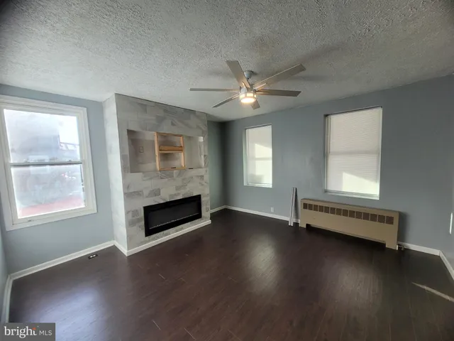 an empty room with windows a fireplace and wooden floor