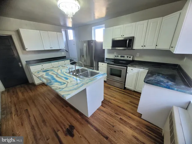 a kitchen with kitchen island granite countertop a stove and a wooden floors