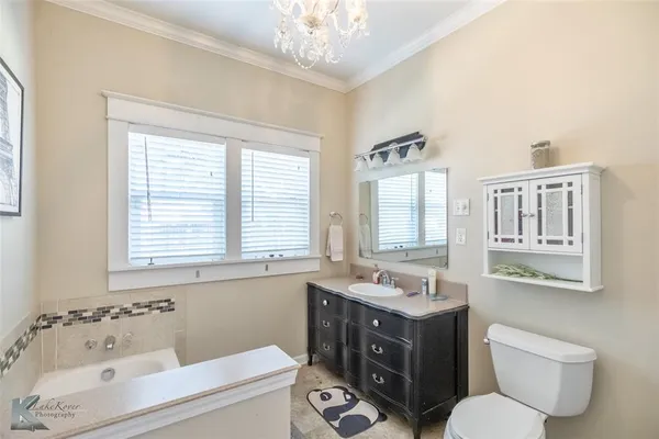 a bathroom with a bathtub sink mirror vanity and a toilet