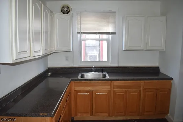 a kitchen with granite countertop a sink a stove and cabinets