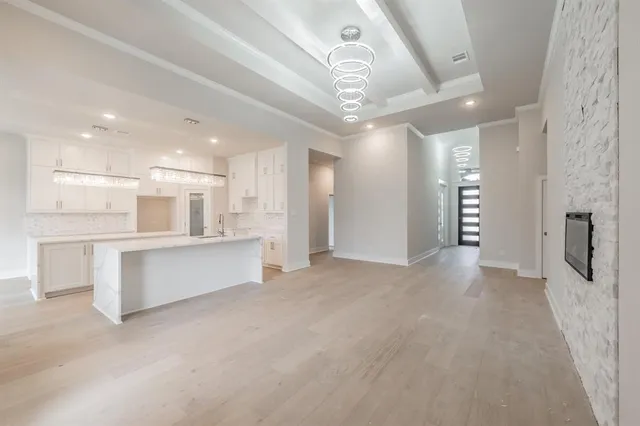 a large white kitchen with lots of counter space wooden floor and stainless steel appliances