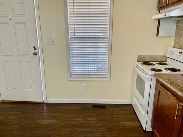 a view of kitchen and empty room with wooden floor