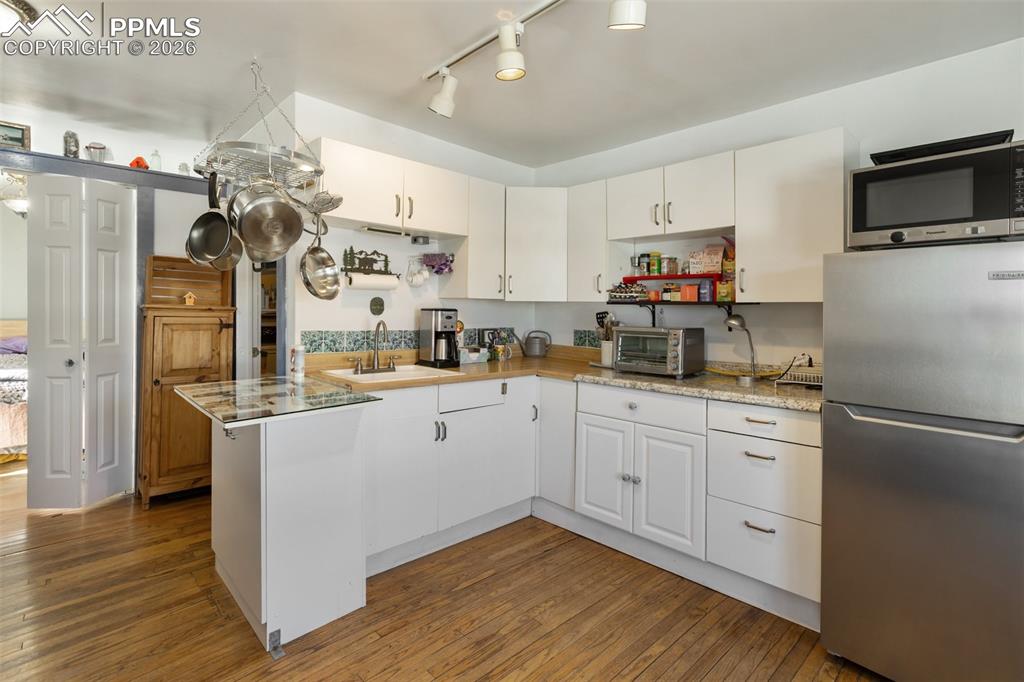 209 5th Street Victor, CO 80860 - Photo 17 of 36 a kitchen with granite countertop a refrigerator a sink and wooden floor