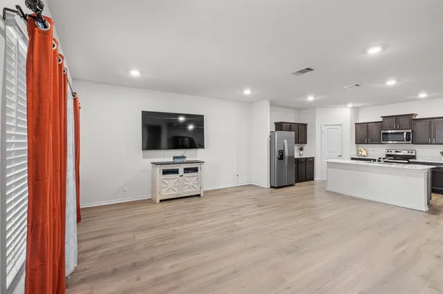 a view of kitchen with microwave oven stove and white cabinets with wooden floor