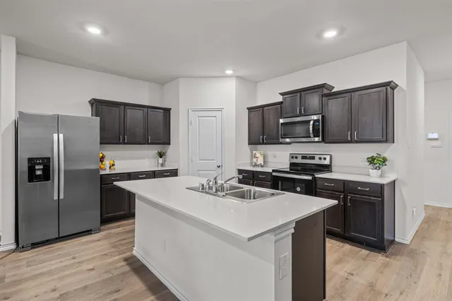 a kitchen with kitchen island a sink stove and refrigerator