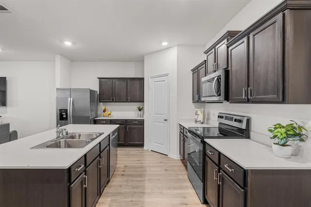 a kitchen with stainless steel appliances granite countertop a sink stove microwave and refrigerator