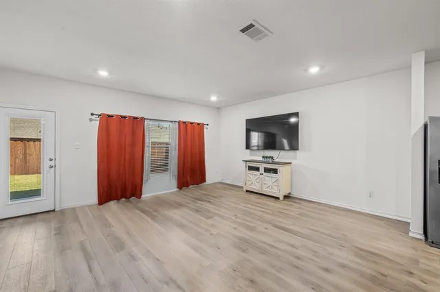 a view of a livingroom with a flat screen tv wooden floor and a ceiling fan