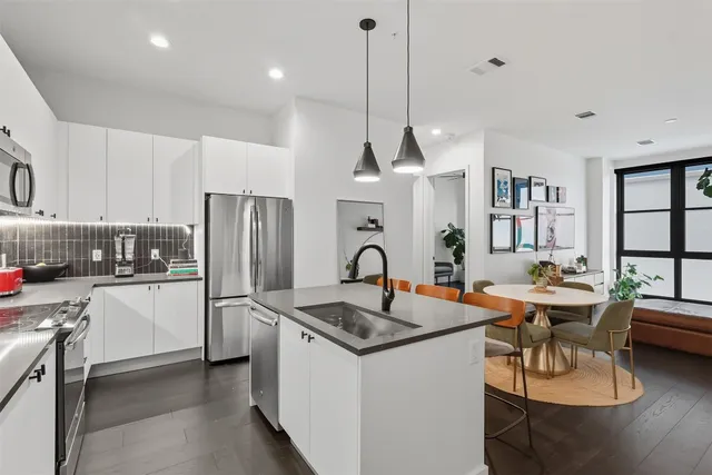 a kitchen with stainless steel appliances granite countertop a sink a stove a refrigerator cabinets a dining table and chairs