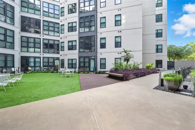 a front view of a building with garden and trees