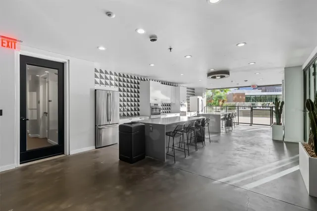 a kitchen with stainless steel appliances granite countertop a refrigerator a sink a stove and a dining table with wooden floor