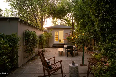 a view of a patio with table and chairs and potted plants with large tree