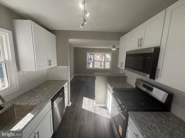 a living room with stainless steel appliances furniture a flat screen tv and a window