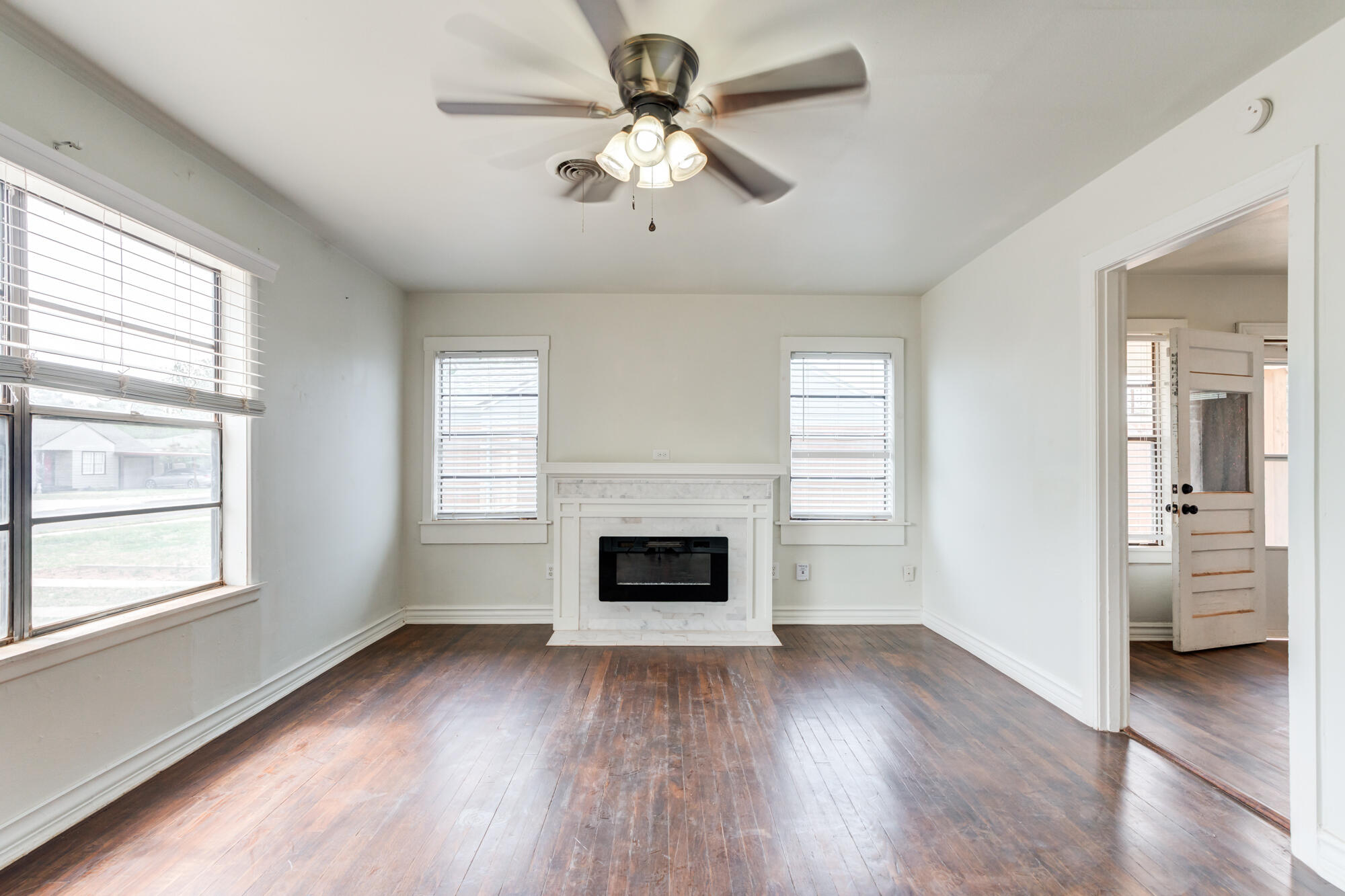 2308 30th Street Lubbock, TX 79411 - Photo 6 of 21 wooden floor fireplace and windows in an empty room
