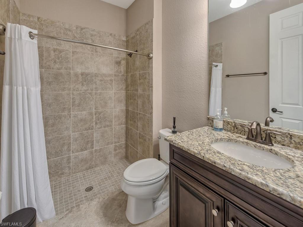 9491 Piacere Way Naples, FL 34113 - Photo 19 of 34 a bathroom with a granite countertop sink a toilet and shower