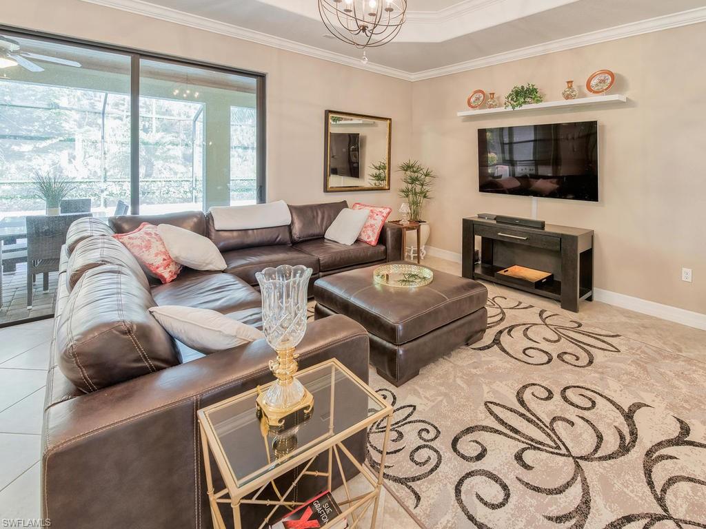 9491 Piacere Way Naples, FL 34113 - Photo 6 of 34 a living room with furniture a flat screen tv and a fireplace