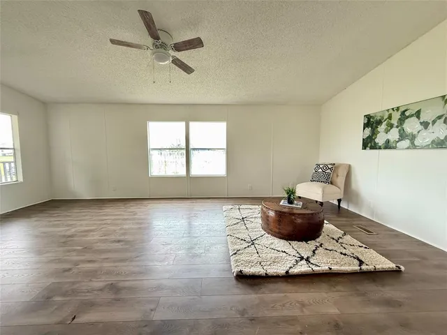 a living room with hard wood floor and a ceiling fan