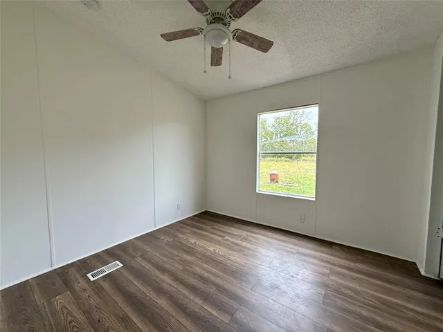 an empty room with windows and ceiling fan