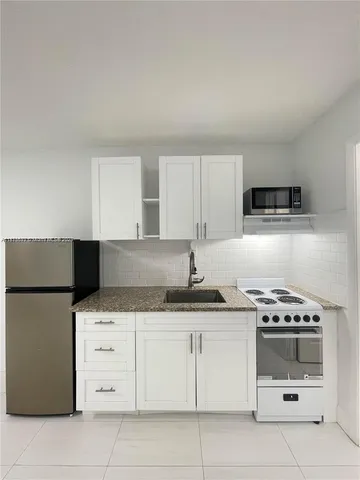a kitchen with granite countertop a stove a sink and a refrigerator