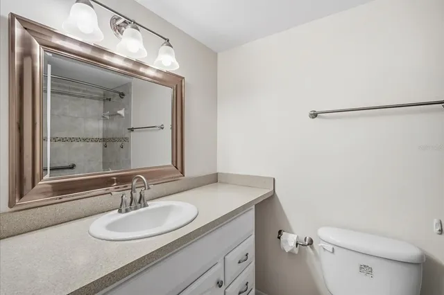 a bathroom with a granite countertop sink mirror vanity and toilet