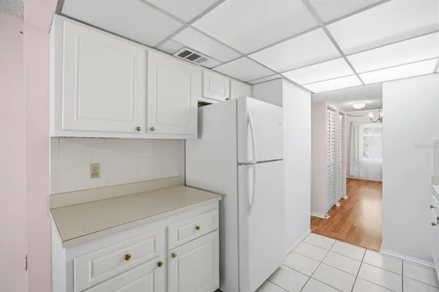 a view of a refrigerator in kitchen and white cabinets