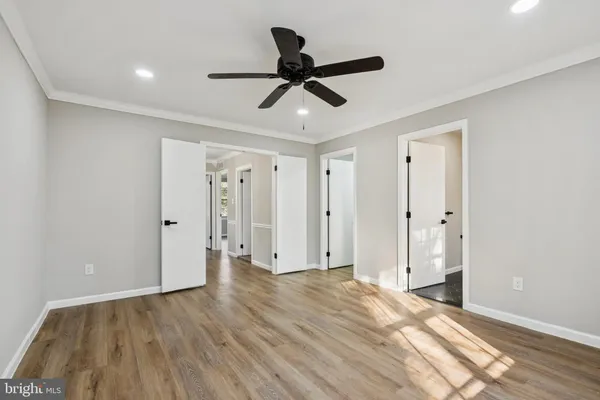 a view of empty room with wooden floor and ceiling fan