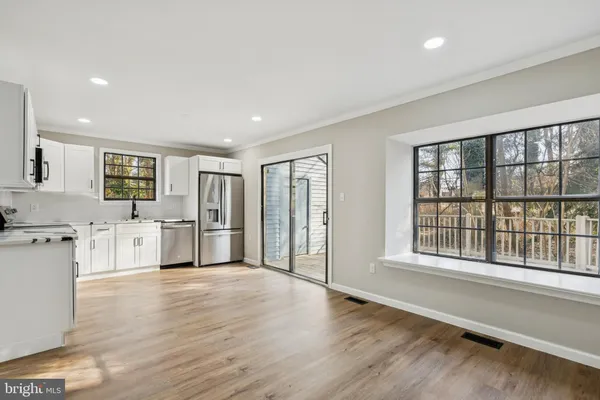 a large white kitchen with stainless steel appliances granite countertop a refrigerator oven a sink dishwasher and white cabinets with wooden floor