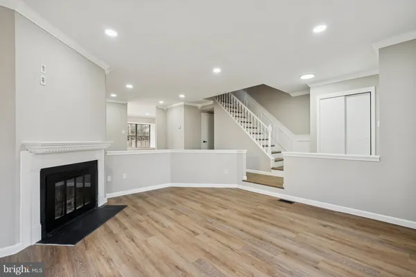 a view of an empty room with wooden floor fireplace and a window