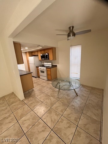 1440 East Vegas Valley Drive, Unit 7 Las Vegas, NV 89169 - Photo 2 of 19 Kitchen featuring dark countertops, brown cabinetry, white gas stove, stainless steel microwave, and a ceiling fan