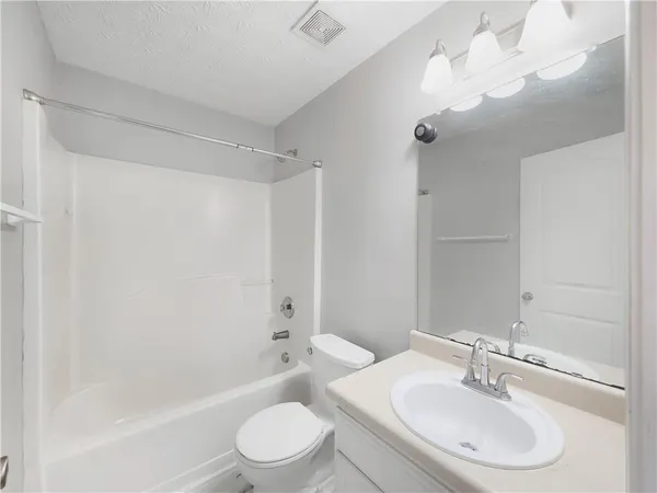 a bathroom with a bathtub shower sink vanity mirror and toilet