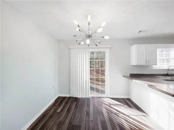 an empty room with wooden floor and a kitchen