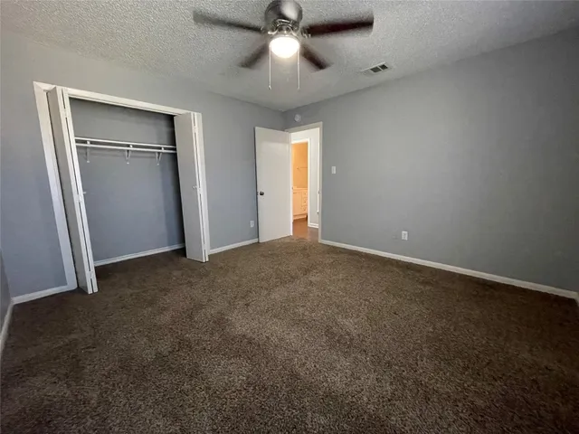 an empty room with closet and a ceiling fan