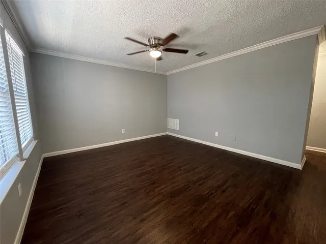 an empty room with wooden floor fan and windows