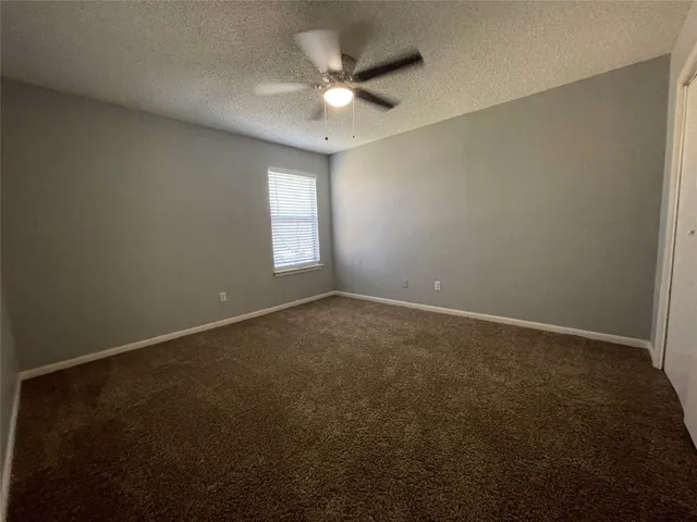 an empty room with a ceiling fan and window
