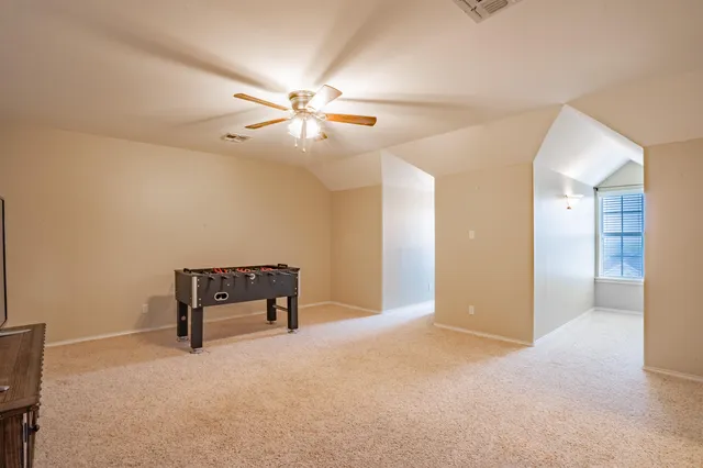 a view of an empty room and chandelier fan