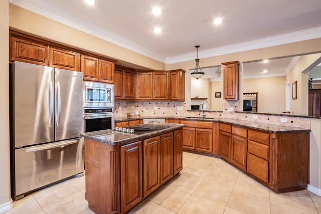 a kitchen with stainless steel appliances granite countertop a refrigerator a sink dishwasher a stove with wooden cabinets and a large window