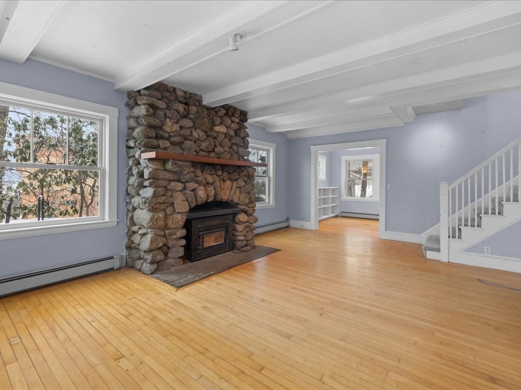 207 Pleasant Street Milton, MA 02186 - Photo 4 of 28 an empty room with windows a fireplace and wooden floor