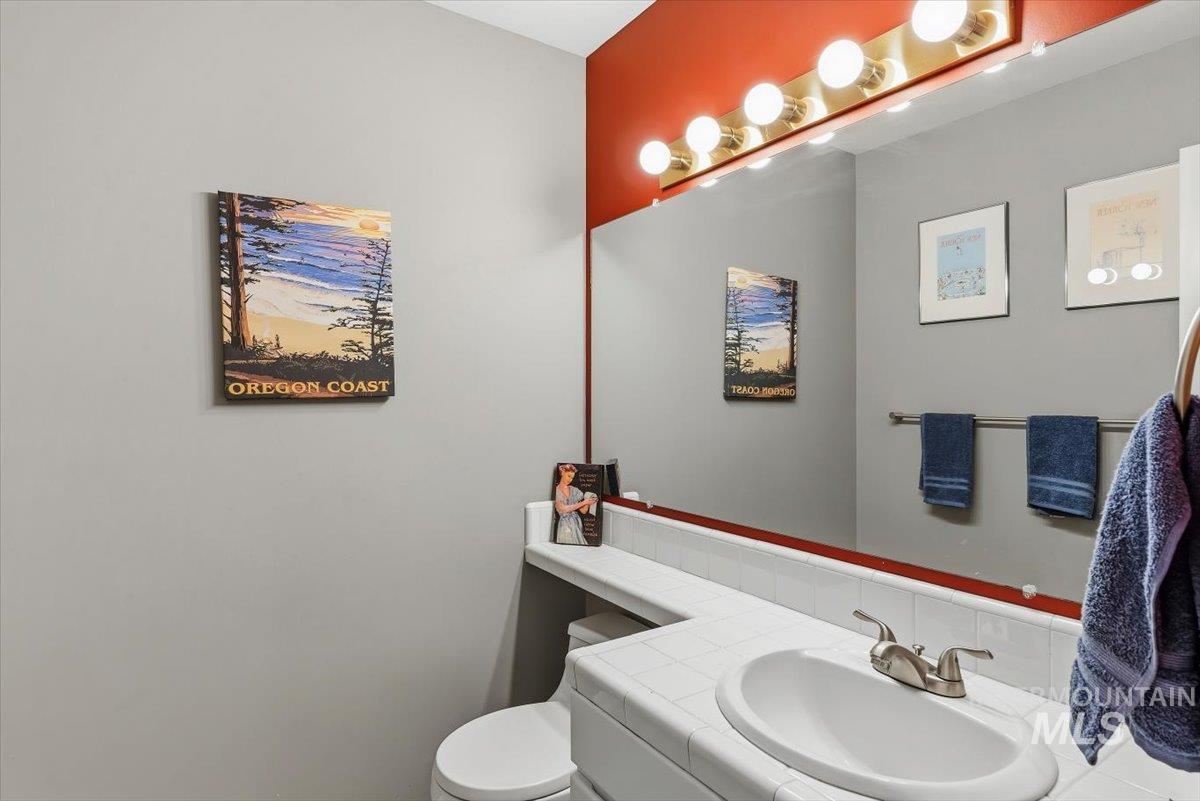 8001 West Innsbrook Court Boise, ID 83704 - Photo 15 of 39 Bathroom featuring a vanity with an integrated sink, a brushed nickel faucet, a full-width mirror, and a multi-bulb vanity light fixture