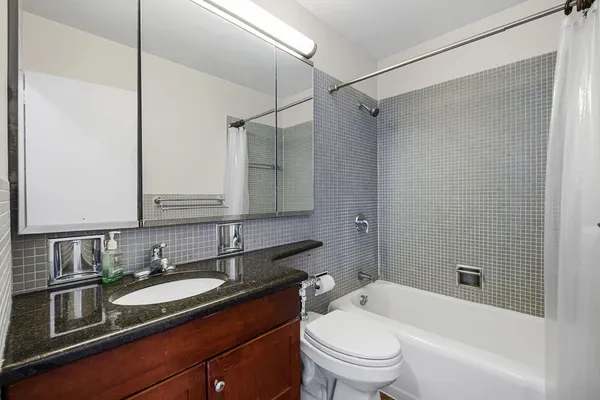 a bathroom with a granite countertop sink a toilet and shower