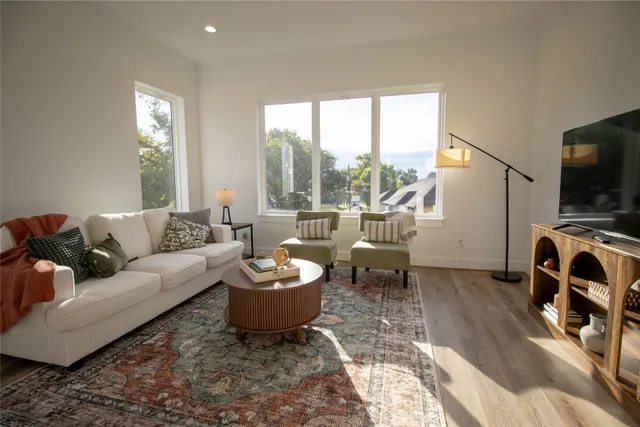 a living room with furniture a flat screen tv and a large window