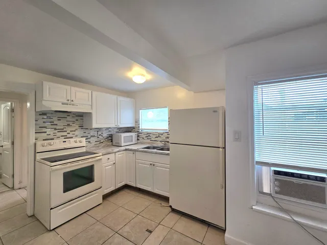 a kitchen with white cabinets and white stainless steel appliances and sink