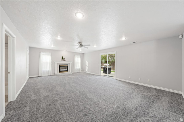 7 Reflection Way St. George, UT 84770 - Photo 18 of 54 Unfurnished living room with a premium fireplace, light carpet, a textured ceiling, ceiling fan, and recessed lighting