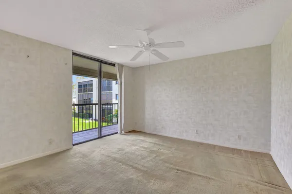 an empty room with floor to ceiling fan and window