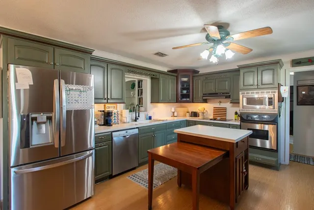 a kitchen with stainless steel appliances granite countertop a refrigerator a sink dishwasher a stove and a refrigerator with wooden floor