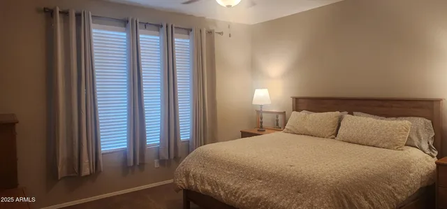 a bed sitting in a bedroom next to a window and a chair