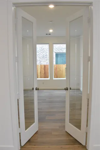 a view of an empty room with wooden floor and a window