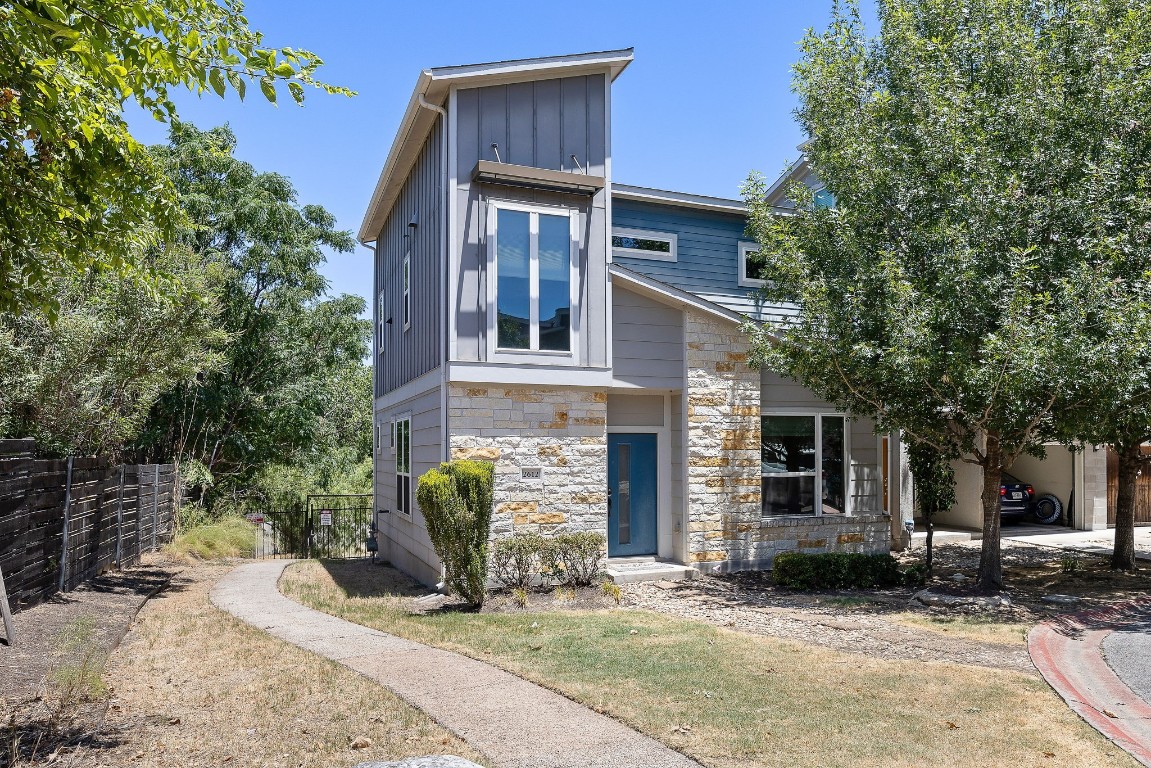 a view of a house with a yard and large tree