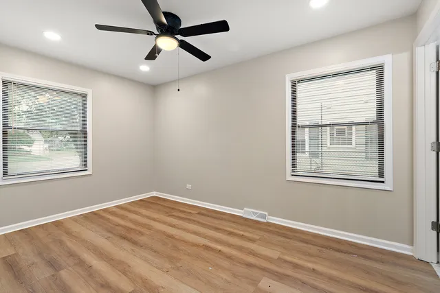 a view of empty room with wooden floor and fan